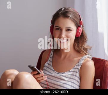 Ma liste de lecture peut vous raconter l'histoire de ma vie. Une jeune femme qui écoute de la musique tout en se relaxant à la maison Banque D'Images