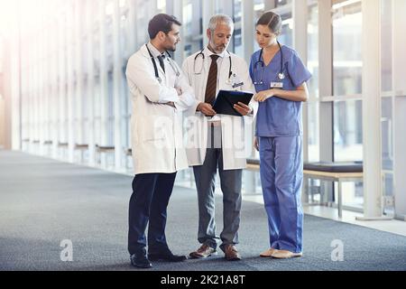 Ils mettent la santé dans les soins de santé. Une équipe médicale regardant un dossier de patients. Banque D'Images