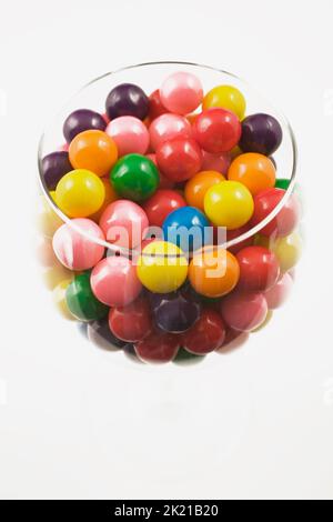 Boules de gomme colorées assorties dans un verre à vin sur fond blanc. Banque D'Images