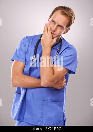 Contempler le meilleur remède. Photo d'un médecin masculin attentif dans des gommages Banque D'Images