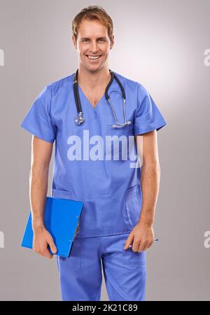 HES heureux d'être la guérison. Un portrait en studio d'un beau médecin souriant tenant une planchette à pince. Banque D'Images