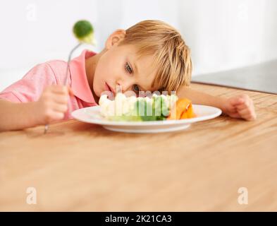 Je n'aime pas les légumes. Un petit garçon très mécontent d'avoir à manger des légumes. Banque D'Images