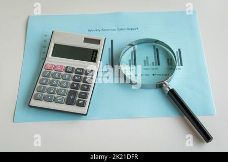 Loupe et calculatrice sur le rapport de chiffre d'affaires avec graphiques. Concept de performance d'entreprise. Banque D'Images