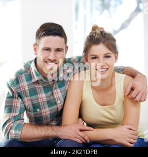 Chaque histoire d'amour est belle, mais la nôtre est mon préféré. Portrait d'un jeune couple aimant assis les uns à côté des autres à la maison. Banque D'Images