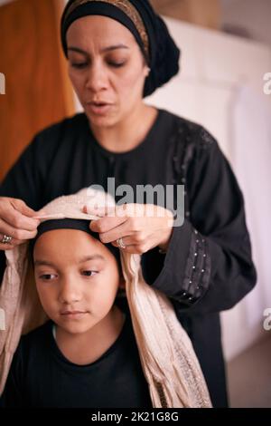 Les traditions sont un lien fort : une mère qui aide sa fille à mettre un foulard Banque D'Images