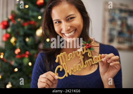 Son bonheur infecte tout le monde qu'elle rencontre. Une belle jeune femme tenant une décoration festive. Banque D'Images