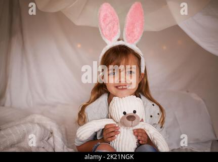 Mon ami furry. Portrait d'une adorable petite fille portant des oreilles de lapin et tenant son lapin jouet Banque D'Images