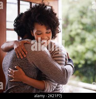 Saluez-la avec une étreinte chaleureuse. Une jeune femme saluant son mari à la porte Banque D'Images