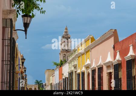 De vieux bâtiments colorés et des lampes de rue bordent une rue avec une tour d'église émergeant au-dessus - à Campeche, au Mexique Banque D'Images