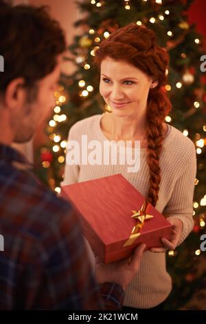 Un jeune couple affectueux qui échange des cadeaux à Noël. Banque D'Images