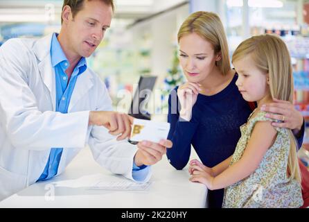 C'est le dosage approprié ici. Un pharmacien donnant des médicaments à une mère et à une fille Banque D'Images