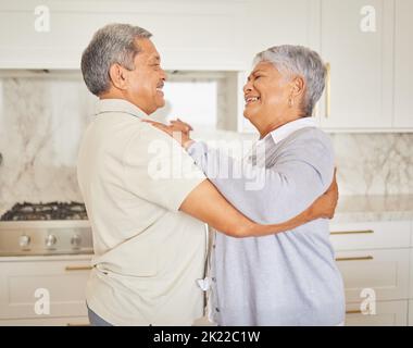 Amour, heureux et vieux couple dansez dans une cuisine à la maison, liant et s'amuser. Homme et femme mûrs se câlin, jouant et aimant, appréciant leur Banque D'Images