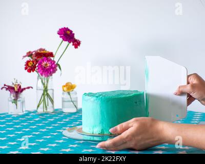 Femme étalant le glaçage pour couvrir le dessus du gâteau. Cuisine maison, faite à la main. Temps libre en quarantaine. Les mains des femmes tiennent le niveleur blanc pour mettre à niveau le Banque D'Images