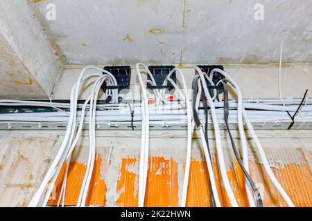 Les câbles sont suspendus au plafond du bâtiment en cours de construction, travaux en cours. Positionnement des fils et des câbles électriques. Banque D'Images