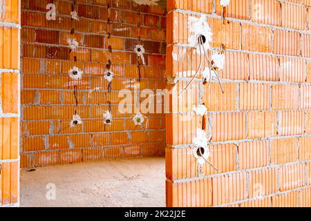 Prises électriques exposées avec les capots supérieurs retirés pour l'installation du câblage sur le mur avec des blocs de bâtiment en construction. Banque D'Images