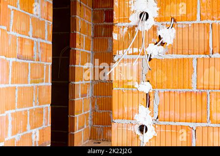 Prises électriques exposées avec les capots supérieurs retirés pour l'installation du câblage sur le mur avec des blocs de bâtiment en construction. Banque D'Images