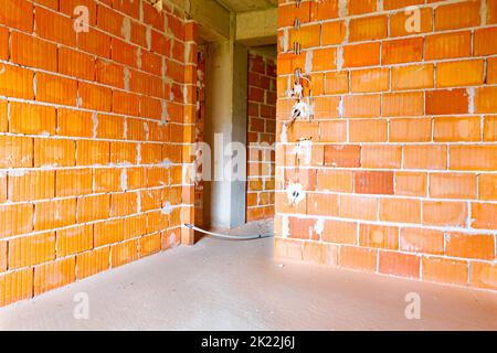 Prises électriques exposées avec les capots supérieurs retirés pour l'installation du câblage sur le mur avec des blocs de bâtiment en construction. Banque D'Images