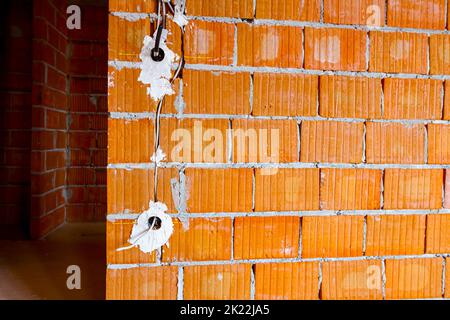 Prises électriques exposées avec les capots supérieurs retirés pour l'installation du câblage sur le mur avec des blocs de bâtiment en construction. Banque D'Images