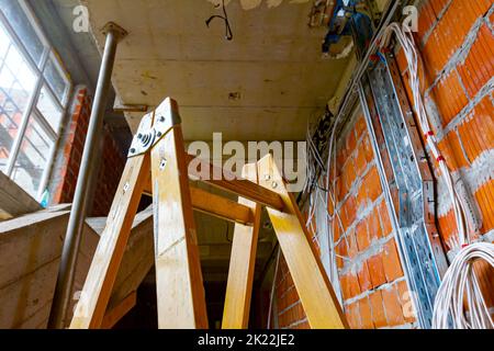 Échelles pour faciliter l'installation des câbles, boîtes de distribution pour l'électricité. Un tas de câbles sont suspendus du plafond, passant entre les planchers i Banque D'Images