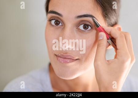 Se débarrasser des poils indésirables. Une jeune femme qui bruitait ses sourcils. Banque D'Images