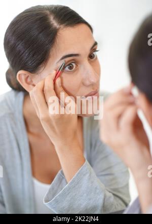 Se débarrasser des poils indésirables. Une jeune femme qui bruitait ses sourcils. Banque D'Images