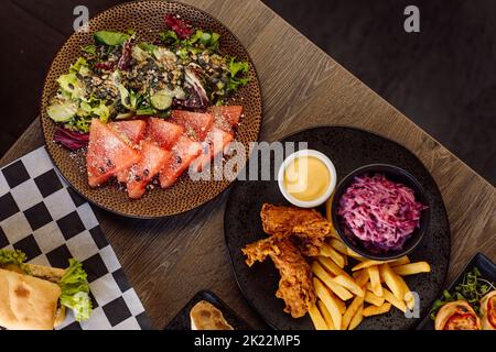 Menu du café et assortiment de plats. Salade de poisson sashimi au saumon, légumes sur l'assiette et poulet rôti aux frites Banque D'Images