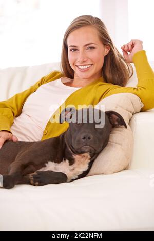 Je me rafraîchis avec mon ami. Portrait d'une jeune femme attirante et de son chien sur le canapé. Banque D'Images