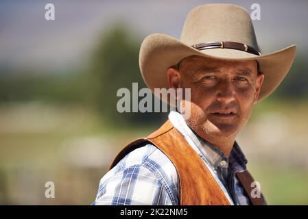 HES le wrangler des bêtes. Un cowboy mature à l'extérieur sur sa ferme. Banque D'Images