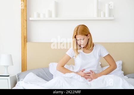 Douleur d'époque. Problème gynécologique. Soins de santé féminins. Lutte menstruelle. Malheureuse souffrance jeune femme au lit avec le ventre abdominal crampes mal dans le lig Banque D'Images