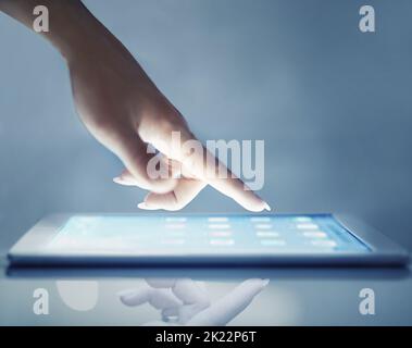 Technologie intuitive. Gros plan court d'une main de femme au-dessus d'une tablette numérique. Banque D'Images