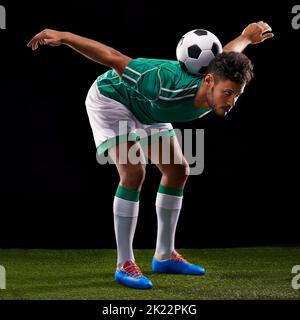 Son contrôle est parfait. Plein studio tourné d'un jeune joueur de football beau isolé sur noir Banque D'Images