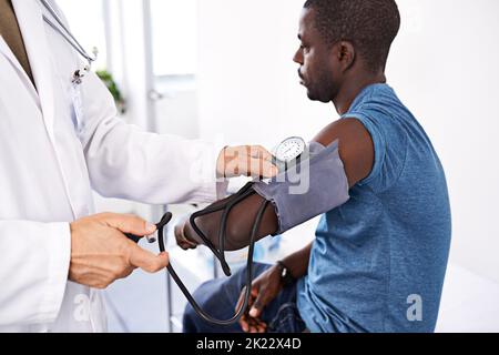 Un médecin qui prend de la tension artérielle chez un patient de sexe masculin. Banque D'Images