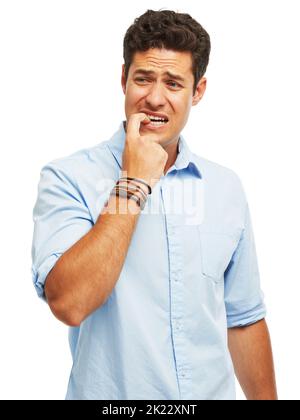 L'incertitude - Une expérience de mise à l'ail. Un beau jeune homme mordant ses ongles dans l'anxiété contre un fond blanc Banque D'Images