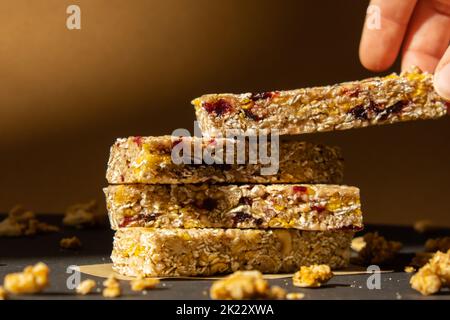 Femme prend le bar énergétique Granola naturel maison. Variété de barres de petit-déjeuner de granola de protéines, avec noix, raisins secs, cerises séchées et chocolat. Nutrition saine alimentation. Collation sans gluten aux céréales Super food Sport Oridge bar Vega dessert concept Banque D'Images