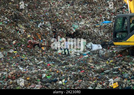 Les moyens d'existence des salariés à revenu très faible travaillant dans les zones polluées dangereuses du déversement de déchets de Chattogram dans Halishahar Chattogram. Les travailleurs collectent les matériaux recyclables de ces tas de déchets tout au long de la journée et les déposent dans des ateliers de ferraille. En tant que commerçants, ils travaillent ici toute la journée et prennent des risques sanitaires extrêmes. Chattogram, Bangladesh. Banque D'Images