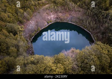 Petit lac bleu cratère d'un volcan dormant entouré de forêt aux couleurs automnales en Allemagne Banque D'Images