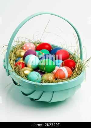 Mettre tous les œufs dans un panier. Photo studio d'un assortiment d'œufs joliment décorés dans un panier de paille Banque D'Images