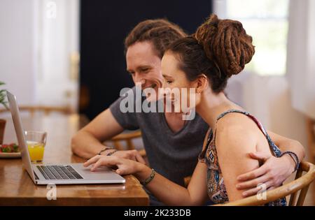 C'est peut-être le cas. Un couple heureux avec des dreadlocks utilisant un ordinateur portable ensemble Banque D'Images