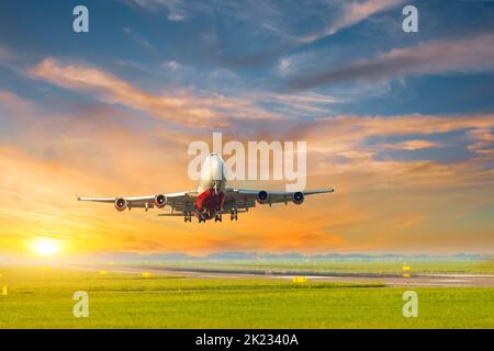 L'avion prend son envol pendant un beau coucher de soleil depuis la piste, sur fond d'un magnifique ciel jaune de coucher de soleil Banque D'Images
