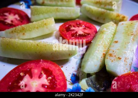 A green Salad Plate with cucumber and tomatoes, Sprinkled spices on top. Vegan Diet. India. Stock Photo