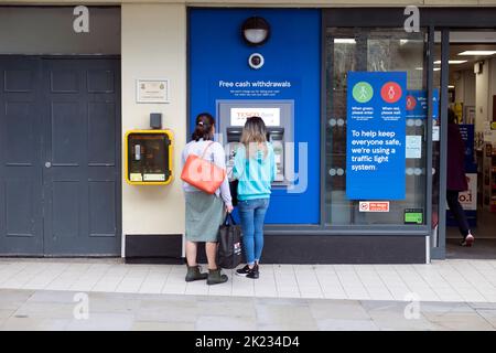 Vue extérieure de la boutique Tesco Extra clients les gens qui utilisent un distributeur automatique de billets à l'extérieur de l'épicerie à Tenby Pembrokeshire South Wales UK Banque D'Images