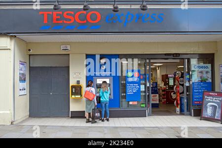 Vue extérieure de la boutique Tesco Extra clients les gens qui utilisent un distributeur automatique de billets à l'extérieur de l'épicerie à Tenby Pembrokeshire South Wales UK Banque D'Images