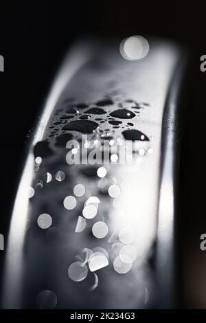 Gouttes d'eau Résumé et avec un arrière-plan flou brille sur une surface métallique d'une chaise. Cliché macro abstrait Banque D'Images