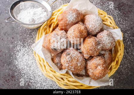 Beignets sucrées oliebollen aux raisins secs et au sucre en poudre dans un panier sur la table. Vue horizontale du dessus Banque D'Images