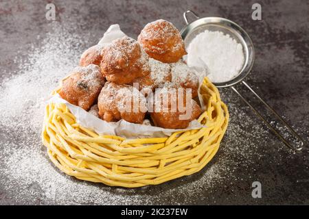 Beignets sucrées oliebollen aux raisins secs et au sucre en poudre dans un panier sur la table. Horizontale Banque D'Images