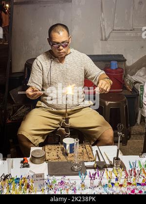 Chiang Mai, Thailand, July 31, 2022 - Glass blower makes new trinket to sell to tourists. Stock Photo