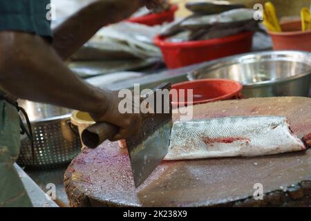 Malaysia, July 10, 2022 - Fish is cut up at market by vendor in Malacca. Stock Photo