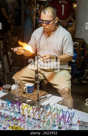 Chiang Mai, Thailand, July 31, 2022 - Glass blower makes new trinket to sell to tourists. Stock Photo