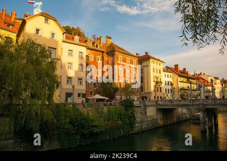 Ljubljana, Slovenia - Sept 3rd 2022. Restaurants and bars on the Ljubljanici River waterfront in Ljubljana. Castle is on the hill on the background Stock Photo