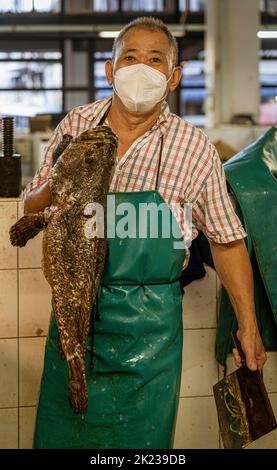 Malaysia, July 10, 2022 - Man holding huge fish he is selling in market vendor. Stock Photo